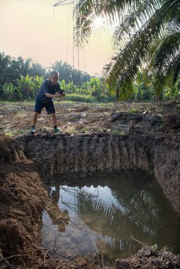 İzole edilmiş çiftlik havuzunda cep telefonuyla fotoğraf çeken bir adam..
