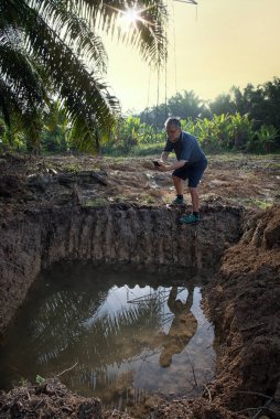 İzole edilmiş çiftlik havuzunda cep telefonuyla fotoğraf çeken bir adam..