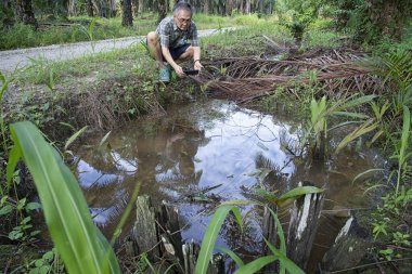 İzole edilmiş çiftlik havuzunda cep telefonuyla fotoğraf çeken bir adam..
