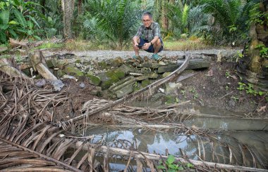 İzole edilmiş çiftlik havuzunda cep telefonuyla fotoğraf çeken bir adam..