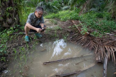 İzole edilmiş çiftlik havuzunda cep telefonuyla fotoğraf çeken bir adam..