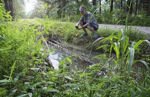 İzole edilmiş çiftlik havuzunda cep telefonuyla fotoğraf çeken bir adam..