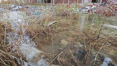 Bitmemiş inşaat binasının etrafında toplanan durgun yağmur suyu havuzu.