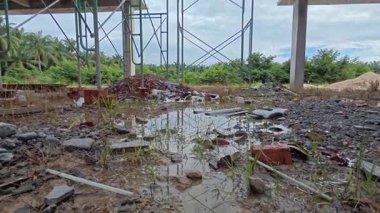 Bitmemiş inşaat binasının etrafında toplanan durgun yağmur suyu havuzu.