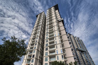 looking up high the cloudy blue sky with the high rise building in the foreground.  