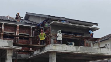 Perak, Malezya. 30 Ekim 2025: Permai İnşaat alanının dış duvarlarını kaplayan bir grup sanayi işçisi çatıda yürüyor.