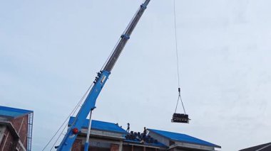 Perak, Malezya. 29 Ekim 2025: Permai inşaat alanındaki yeni binanın çatısındaki işçilere vinç servis kamyonunun çatı bloğunu kaldırması. Kg Koh. 