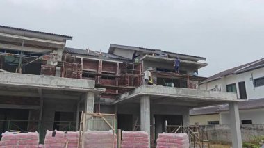 Perak, Malezya. 30 Ekim 2025: Permai İnşaat alanının dış duvarlarını kaplayan bir grup sanayi işçisi çatıda yürüyor. 