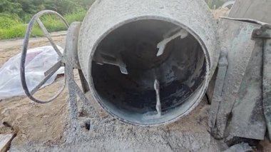 İnşaat alanında çimento kaldırmak için metal kovayla beton karıştırıcı ve ip makarası..