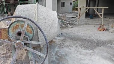 İnşaat alanında çimento kaldırmak için metal kovayla beton karıştırıcı ve ip makarası..