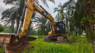 Perak, Malezya. 10 Kasım 2025: Çekiç tarım buldozerli Tırtıl Kazıcısı, izole Palm Petrol Çiftliği 'ne park etmiş pist tipi traktör, Kg Koh.