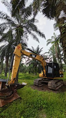 Perak, Malezya. 10 Kasım 2025: Çekiç tarım buldozerli Tırtıl Kazıcısı, izole Palm Petrol Çiftliği 'ne park etmiş pist tipi traktör, Kg Koh.