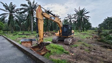 Perak, Malezya. 10 Kasım 2025: Çekiç tarım buldozerli Tırtıl Kazıcısı, izole Palm Petrol Çiftliği 'ne park etmiş pist tipi traktör, Kg Koh.