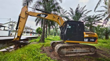Perak, Malezya. 10 Kasım 2025: Çekiç tarım buldozerli Tırtıl Kazıcısı, izole Palm Petrol Çiftliği 'ne park etmiş pist tipi traktör, Kg Koh.