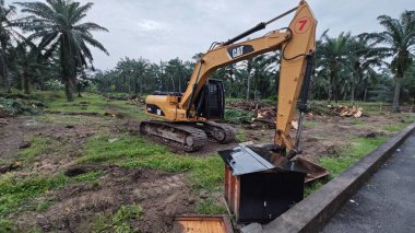 Perak, Malezya. 10 Kasım 2025: Çekiç tarım buldozerli Tırtıl Kazıcısı, izole Palm Petrol Çiftliği 'ne park etmiş pist tipi traktör, Kg Koh.