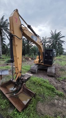 Perak, Malezya. 10 Kasım 2025: Çekiç tarım buldozerli Tırtıl Kazıcısı, izole Palm Petrol Çiftliği 'ne park etmiş pist tipi traktör, Kg Koh.