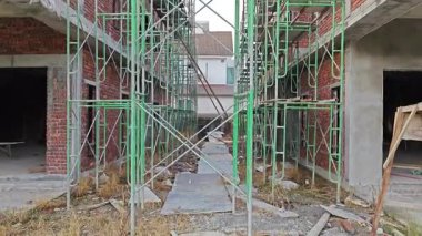 Çimento duvar sıva sırasında işçilerin ayakta durabilmesi için geçici olarak yükseltilmiş platform veya yapı iskeleti sahnesi. 