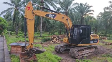 Perak, Malezya. 10 Kasım 2025: Çekiç tarım buldozerli Tırtıl Kazıcısı, izole Palm Petrol Çiftliği 'ne park etmiş pist tipi traktör, Kg Koh.