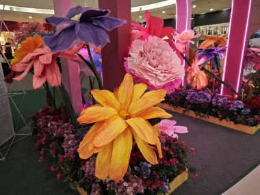 Perak, Malezya. 10 Kasım 2025: Aeon Alışveriş Kompleksi girişi Sri Manjung 'un merkezinde güzel renkli dev boyutta plastik çiçek süslemesi.