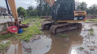 Perak, Malezya. 25 Kasım 2025: Çekiç buldozerli Tırtıl Kazıcısı izole edilmiş Palm Petrol Tarlası 'nın su basmış arazisine park etmiş traktör tipi tekerli, Kg Koh.
