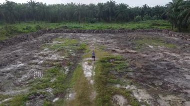 Boş tarım arazisinin temiz ya da düzleştirilmiş arazisinde insansız hava aracı uçuran bir adamın hava görüntüsü..