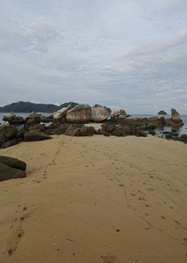 Kumlu sahil kenarında bulunan kayalık kayalara doğru bakıyor..