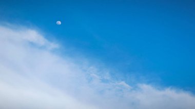 Dolunay yükseldiğinde gündüz vakti mavi gökyüzüne bakarak.