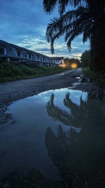 İzole edilmiş toprak yolun gece manzarası. Yakınlardaki sokak lambası alanına doğru gölet çukurları var..