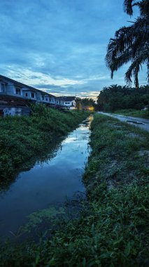 İzole edilmiş toprak yolun gece manzarası. Yakınlardaki sokak lambası alanına doğru gölet çukurları var..