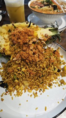 Bir tabak taze ananas meyvesi ve içinde kızarmış pirinç malzemesi var..