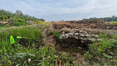 Yeni sürülmüş topraklarda basit bir adamın drenaj sistemi oluşturduğu sahne.