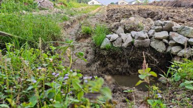 Yeni sürülmüş topraklarda basit bir adamın drenaj sistemi oluşturduğu sahne.