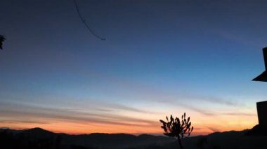 Tepenin zirvesi, vadi sahnesiyle birlikte altın saatinde renkli gökyüzüne doğru bakıyor..