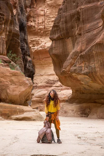 身着黄色衬衫、背着背包的女游客站在峡谷的底部，抬头看 — 图库照片