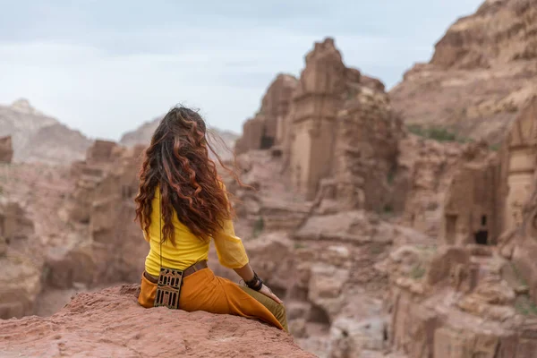 Una joven turista se sienta en el borde de un acantilado en un cañón y mira a la distancia — Foto de Stock