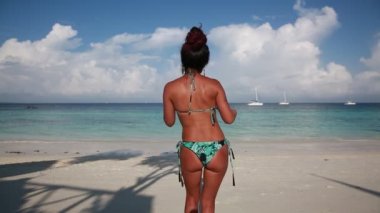 Mayolu güzel bir kız sahilde dans ediyor, güzel bir şekilde poposunu sallıyor.