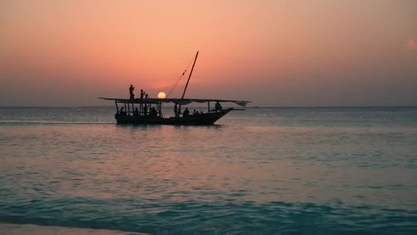 Het silhouet van een fregat zweeft aan de horizon langs de zee tegen de achtergrond van een kleurrijke zonsondergang — Stockvideo