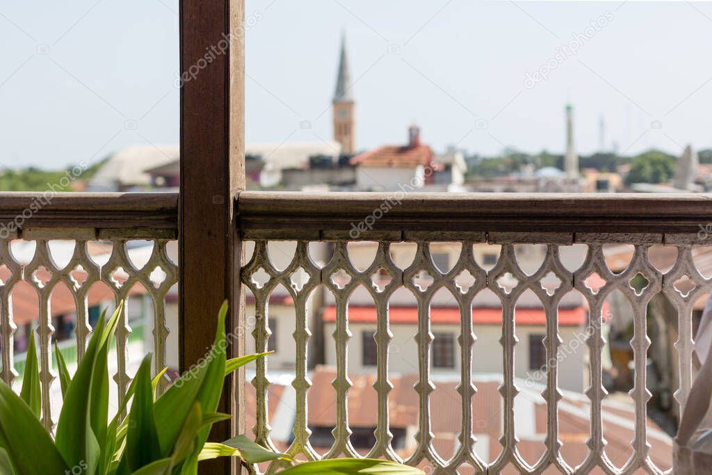 View through the carved balcony railing on the old town. The fence is in focus, the city is out of focus.