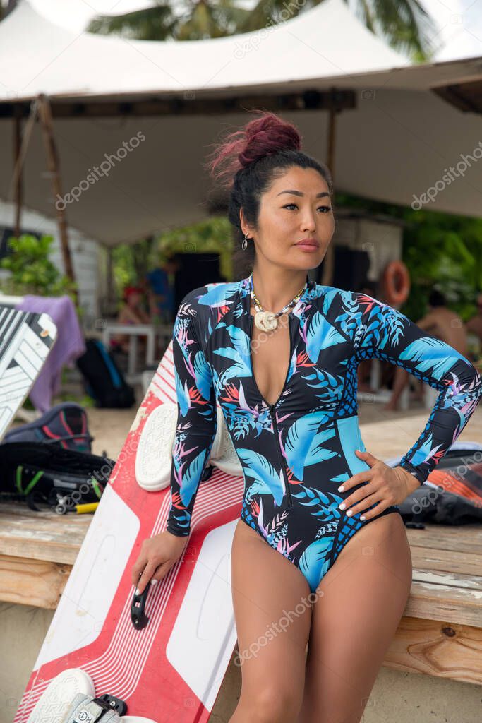 Beautiful girl, kitesurfer in excellent sports form is resting after riding on a board