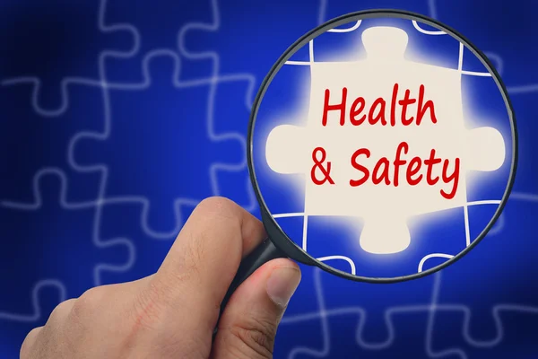 Health and safety word. Magnifier and puzzles. — Zdjęcie stockowe