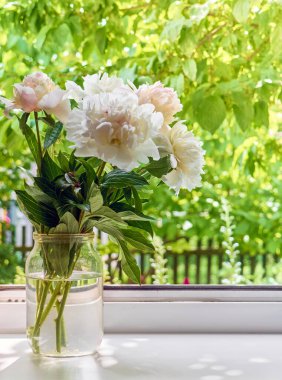 Pencere kenarındaki vazoda şakayık demeti.