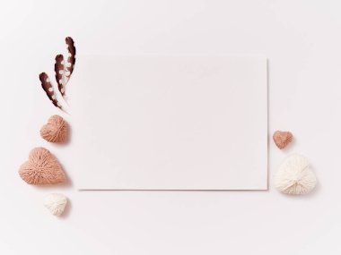 El yapımı el yapımı kalpler ve beyaz arka planda tüy olan kartpostal.