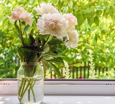 Pencere kenarındaki vazoda şakayık demeti.