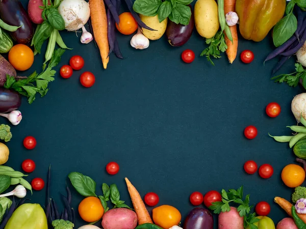 Koyu arka planda çeşitli sebzelerin çerçevesi, üst görünüm.