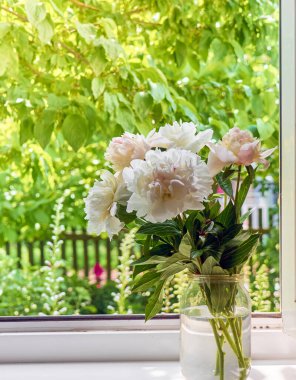 Pencere kenarındaki vazoda şakayık demeti.