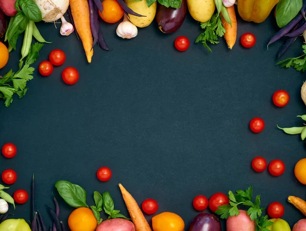 Koyu arka planda çeşitli sebzelerin çerçevesi, üst görünüm.