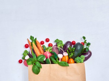 Beyaz arka planda kağıt torbalarda sebzeler.