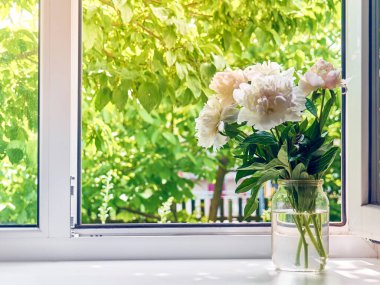 Pencere kenarındaki vazoda şakayık demeti.