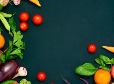 Koyu arka planda çeşitli sebzelerin çerçevesi, üst görünüm.