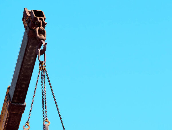 Yellow telescopic hydraulic boom of truck crane on blue sky background